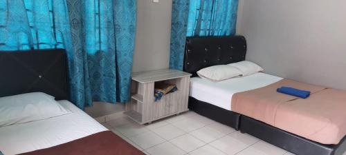 a bedroom with two beds and blue curtains at Sobey Laris Roomstay IMAN GMC in Gua Musang