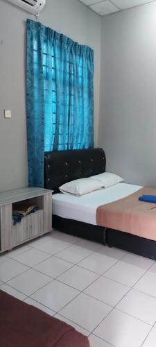 a bedroom with two beds and a blue curtain at Sobey Laris Roomstay IMAN GMC in Gua Musang