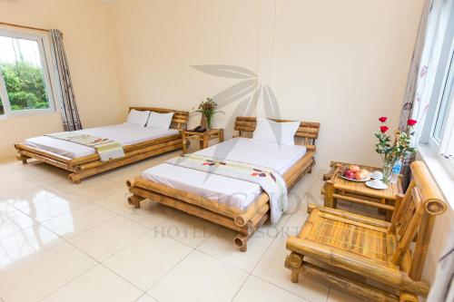 Tre Nguồn Thiên Cầm Hotel&Resort في Hưng Long: غرفة نوم بسريرين وطاولة مع ورد