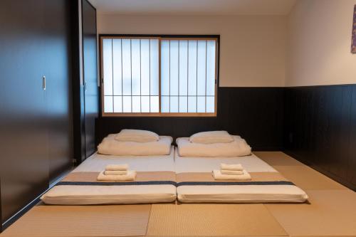 two beds in a room with a window at Irodori Hotel TOU in Fukuoka