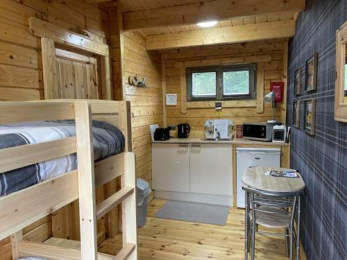a bedroom with a bunk bed and a kitchen in a log cabin at Immaculate cabin 5 mins to Inverness dogs welcome in Inverness