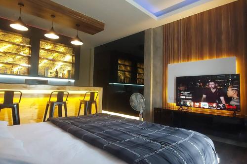 a bedroom with a bed and a bar with a tv at Lanmuanghouse in Chiang Rai