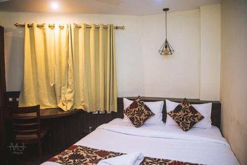 a bedroom with two beds and yellow curtains at Rajdarbar Hotel & Banquet, Siliguri in Siliguri