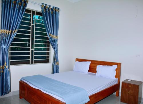 a bedroom with a bed and a window with blue curtains at Vinh Airport Hotel in Vinh