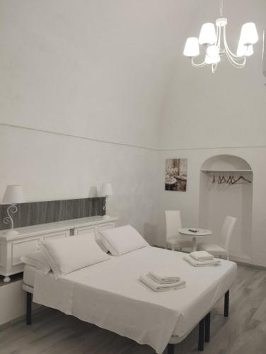 a white bedroom with a bed and a chandelier at La Maison Piazza del Popolo in Manfredonia