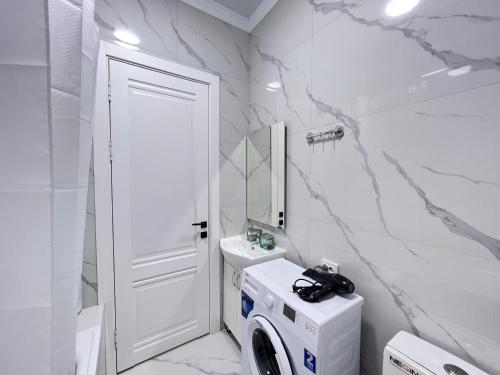a white bathroom with a washer and dryer in it at ЖК «Комфорт Сити» in Almaty
