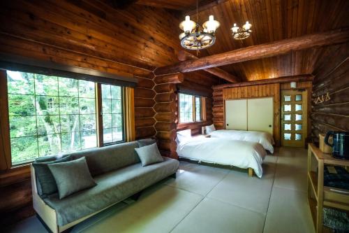 ein Wohnzimmer mit einem Sofa, einem Bett und Fenstern in der Unterkunft Hacho no Yu in Nikko