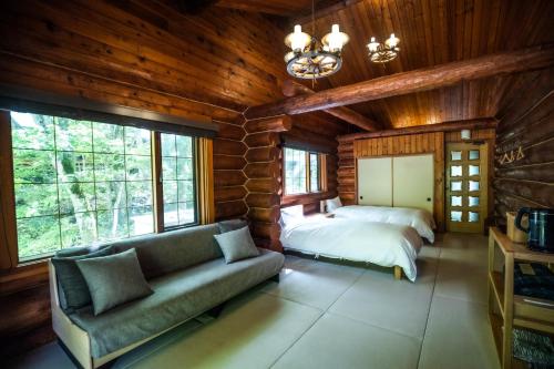 a living room with a couch and a bed and windows at Hacho no Yu in Nikko