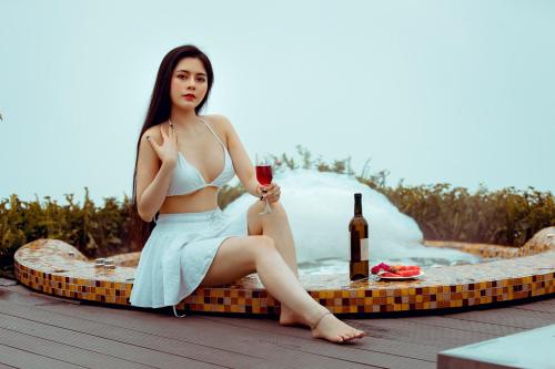 Eine Frau, die auf einem Tisch mit einem Glas Wein sitzt. in der Unterkunft Phuong Nam Hotel in Sa Pa