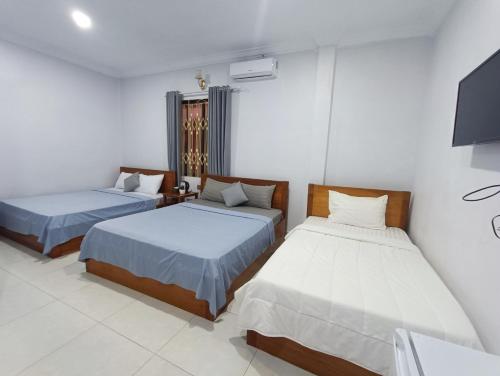 a bedroom with two beds and a tv at Orchid 101 in Kampot