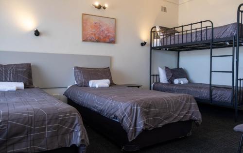 two beds in a room with two bunk beds at Doonside Hotel in Doonside