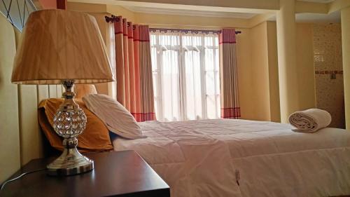 1 dormitorio con 1 cama con lámpara y ventana en Apartamento amplio, cómodo y desestresante!!! en Cochabamba