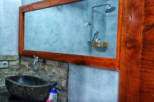 uma casa de banho com um espelho e um lavatório com um chuveiro em triangle cottage bali em Ambengan