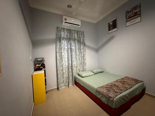 Raudah Homestay في كوتا بْهارو: غرفة نوم صغيرة بها سرير ونافذة