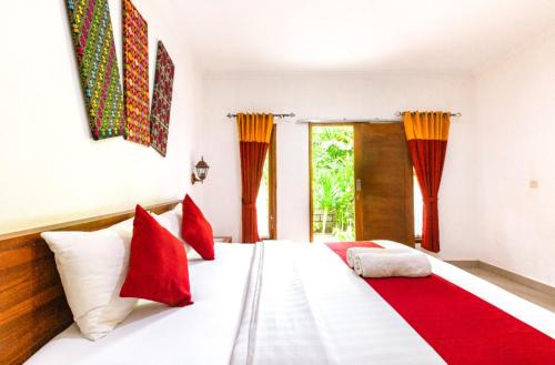 a bedroom with a large white bed with red pillows at Double-G Guest House in Nusa Penida