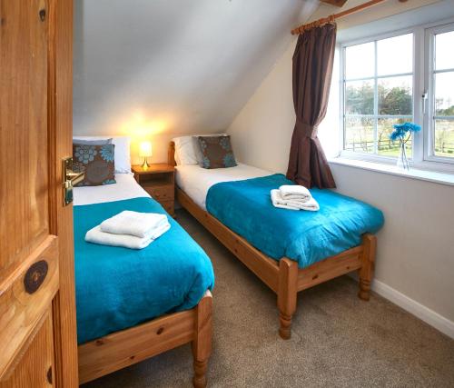 2 łóżka pojedyncze w pokoju z oknem w obiekcie Smugglers Rock Cottage w mieście Ravenscar