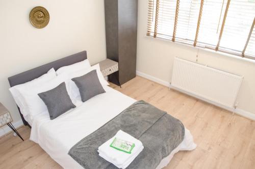 una camera da letto con un letto bianco con un libro verde sopra di NEW 2BD Detached House in the Heart of Lincoln a North Hykeham