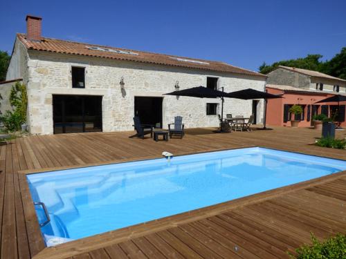 une grande piscine bleue sur une terrasse en bois dans l'établissement La Grange d'Aunis, à Aigrefeuille-dʼAunis