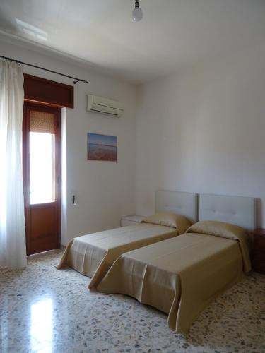 two beds in a white room with a door at Bed&Belvedere in Otranto