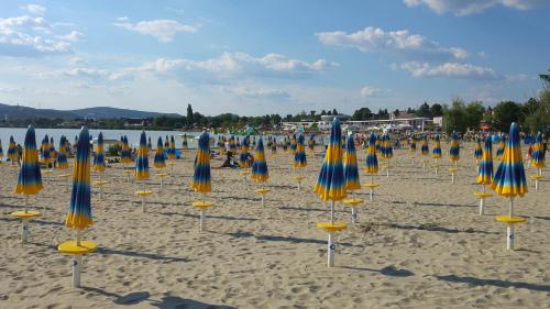 a bunch of umbrellas and chairs on a beach at CSAOL Apartman ház in Velence