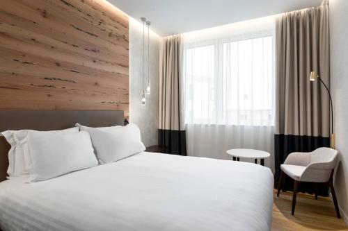 una camera d'albergo con un letto bianco e una sedia di AC Hotel Venezia by Marriott a Venezia