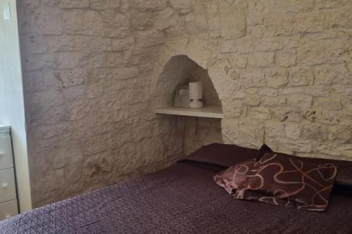 ein Schlafzimmer mit einer Steinmauer und einem Bett in der Unterkunft Trullo Mancini in Locorotondo