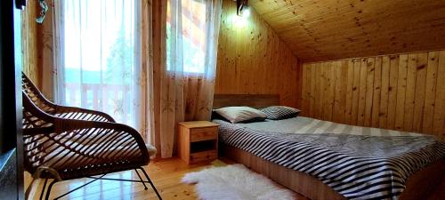ein Schlafzimmer mit einem Bett, einem Stuhl und einem Fenster in der Unterkunft Cabana Ana in Muntele Rece