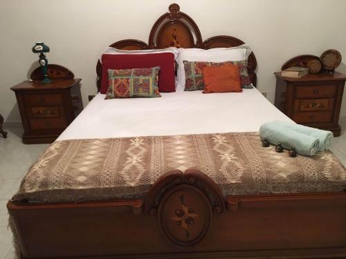 a bedroom with a large wooden bed with pillows at RENT ROOM JOE Via Dante 77 Solarino in Solarino