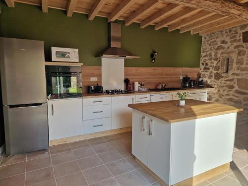 a large kitchen with white cabinets and a refrigerator at Gîte des Catalpas in Vollore-Ville