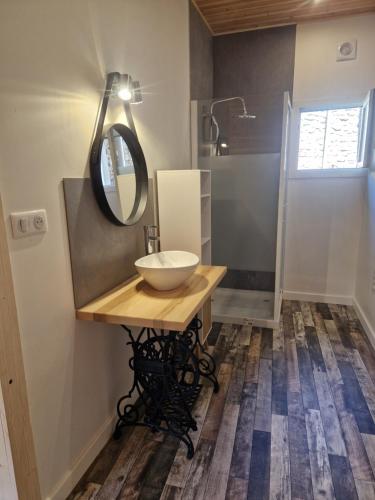 a bathroom with a sink and a mirror on a table at Gîte des Catalpas in Vollore-Ville