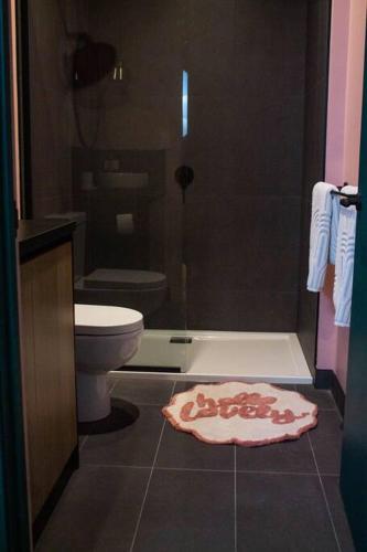 a bathroom with a toilet and a shower and a rug at The Greeen Room in Launceston