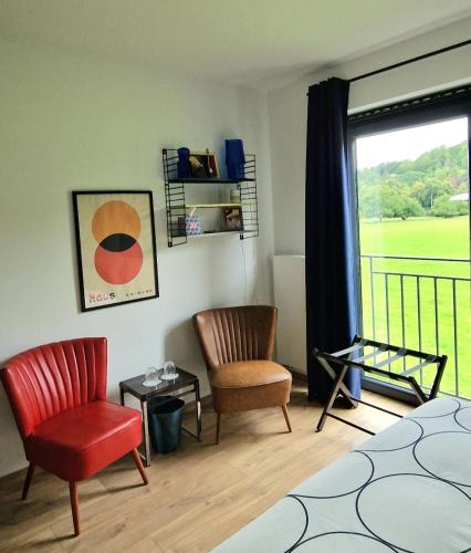 a bedroom with a bed and two chairs and a window at Paulette à bicyclette in Méry