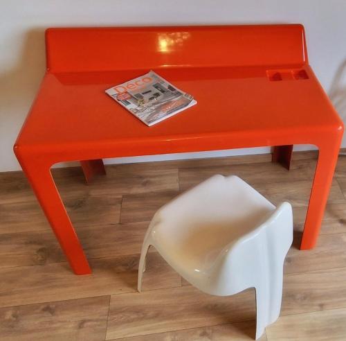 a red table with a white chair next to it at Paulette à bicyclette in Méry
