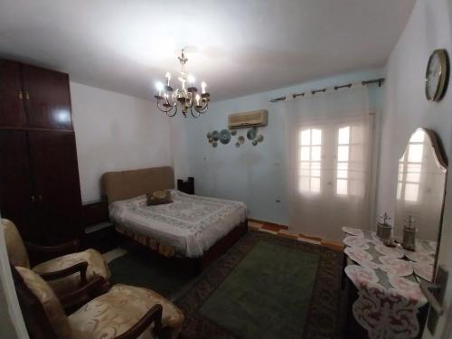 a room with a bed and a table and a chandelier at Shery''s home in 6th Of October