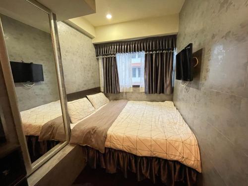 Habitación pequeña con 2 camas y espejo. en 香港美庭旅馆, en Hong Kong