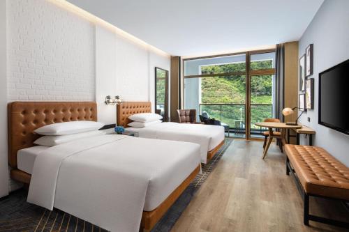 a hotel room with three beds and a television at Four Points by Sheraton Qiandao Lake in Thousand Island Lake