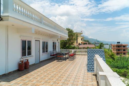a patio of a white house with chairs and tables at The White House Villa 8 bedroom with Swimming Pool in Kathmandu