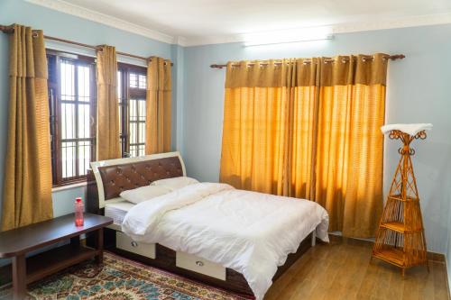 a bedroom with a bed and a table and windows at The White House Villa 8 bedroom with Swimming Pool in Kathmandu