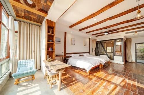 duża sypialnia z łóżkiem, stołem i krzesłami w obiekcie Moganshan 107 Courtyard B&B w mieście Deqing
