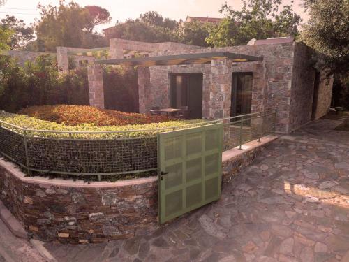 a stone building with a door in a garden at Ouzo Stone Studio in Plomarion