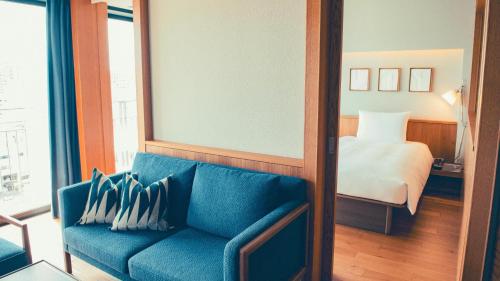 ein Wohnzimmer mit einem blauen Sofa und einem Bett in der Unterkunft Southwest Grand Hotel in Naha