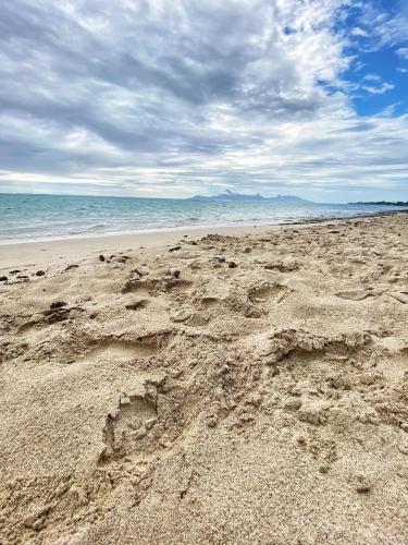 a beach with footprints in the sand and the ocean at Vanakea Beach House in Punaauia