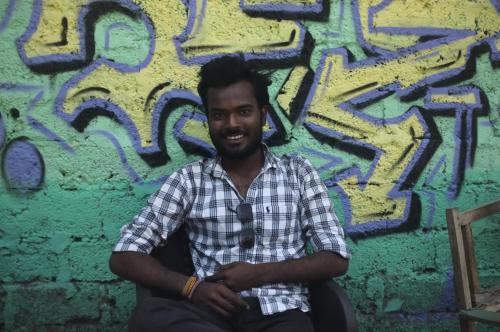 a man sitting in front of a wall with graffiti at Clan Boho in Rishīkesh