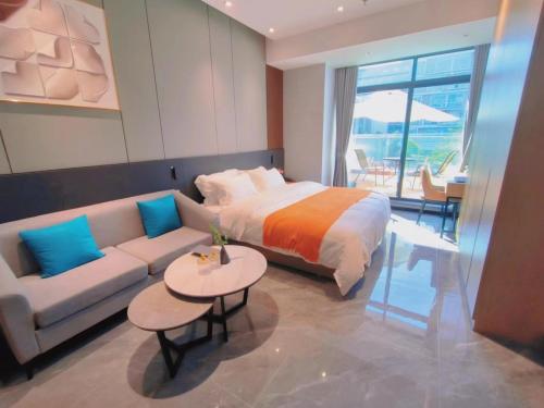 a bedroom with a bed and a couch and a table at Shi Lai De Executive Apartments in Dongguan
