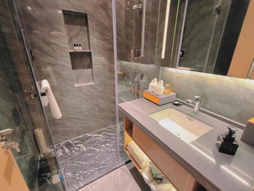 uma casa de banho com um chuveiro, um lavatório e um chuveiro em Shi Lai De Executive Apartments em Dongguan