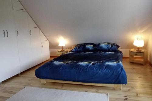 sypialnia z dużym niebieskim łóżkiem z 2 lampami w obiekcie Domek w Narewce w mieście Narewka