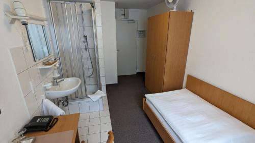 Habitación pequeña con cama y lavamanos en Gästehaus Ziegler, en Stuttgart