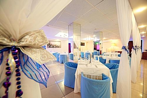 a dining room with white tables and blue chairs at Vladimir Plaza in Bryansk
