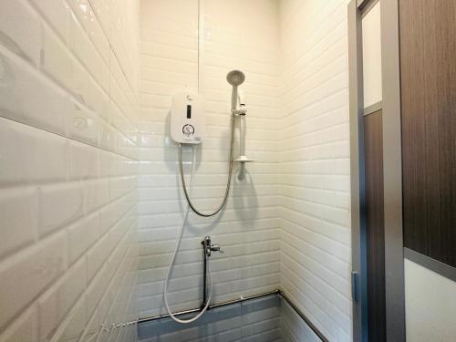 a shower in a white bathroom with a hose at THE ROOM Capsule Hotel in Singapore