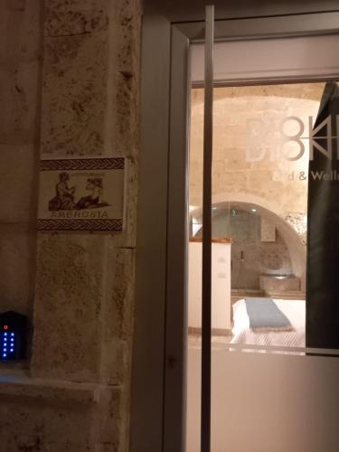 a glass door to a room with a bed in it at DIONISO Bed & Wellness in Taranto